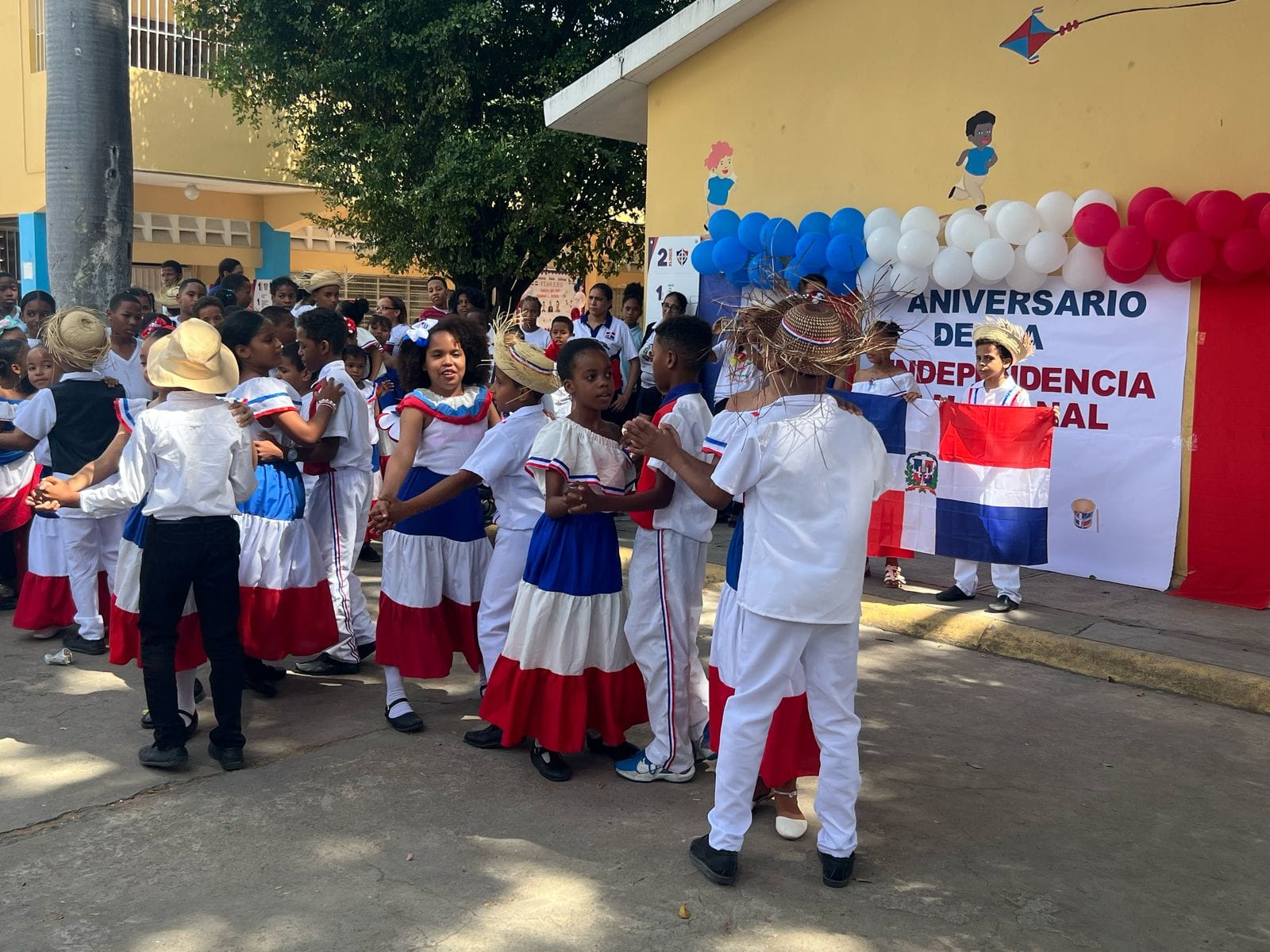 Niños bailando merengue en festival escolar en Los Alcarrizos